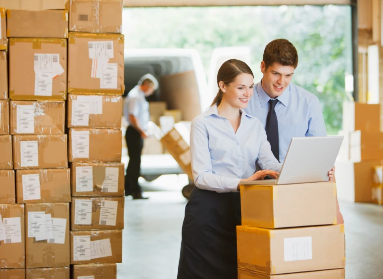 Warehouse workers checking laptop near boxes